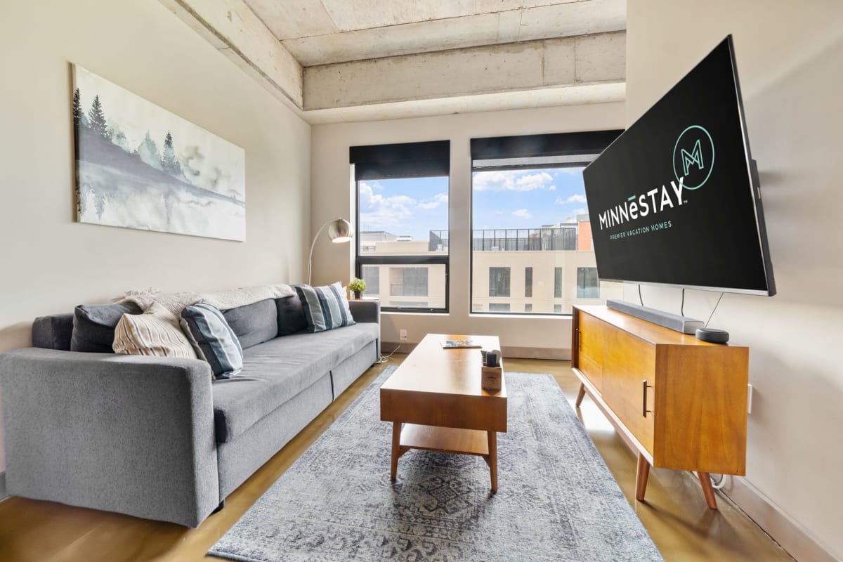 Relax in your modern living room with exposed concrete beams, mid-century furniture, and city views streaming through large windows.