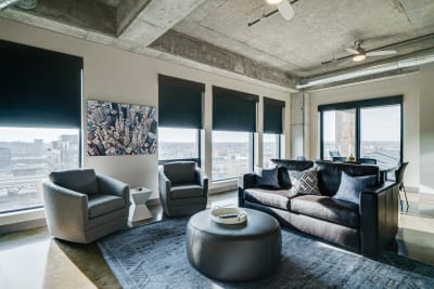 Stylish modern living room featuring leather sofa, gray armchairs, and city skyline art.