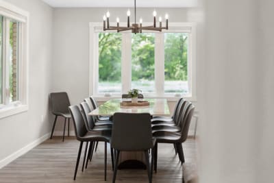 Modern dining area with black chairs, wooden table, and chandelier.