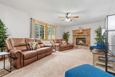 Cozy living room with leather recliners, a brick fireplace, and a blue chair.