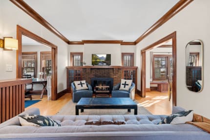 Cozy living room with a brick fireplace, blue armchairs, and a tufted sofa.