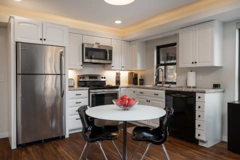 Bright and modern kitchen featuring white cabinets, stainless steel appliances, and a round dining table with apples.