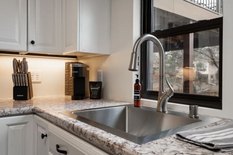 Modern kitchen featuring a stainless steel sink, coffee maker, and knife set on the countertop.