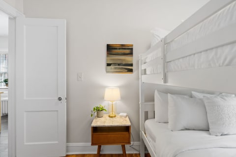 Interior of a bedroom featuring a bunk bed, nightstand, and abstract wall art.