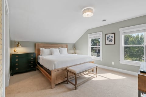 A bedroom with a wooden bed, green walls, and natural light from windows.
