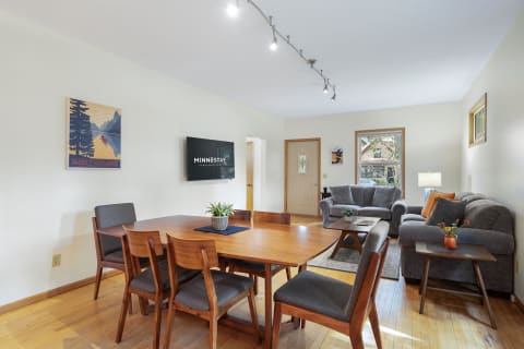 Bright living area featuring a dining table, a gray couch, and wall decor.
