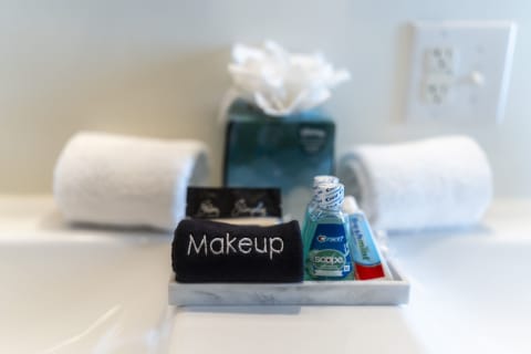 Bathroom countertop with a navy towel labeled 'Makeup,' Crest mouthwash, toothpaste, and two white towels.
