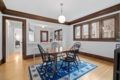 A dining room featuring a wooden table, black chairs, and large windows with natural light.