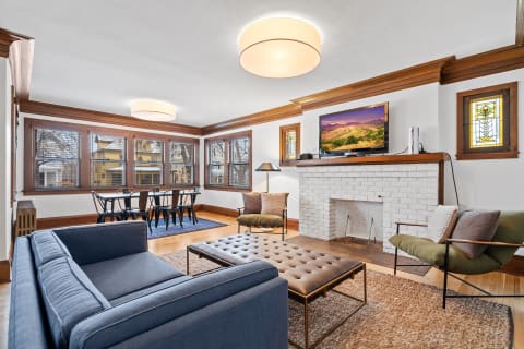 Cozy living room with a blue sofa, tufted coffee table, and a fireplace.