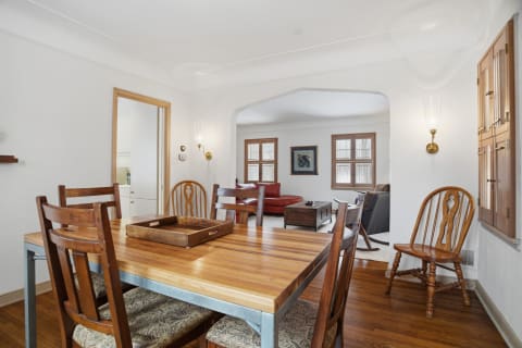 A cozy dining area featuring a wooden table and chairs, with a view into an adjoining living room.
