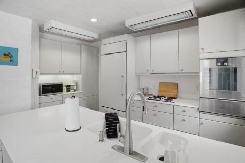 A modern kitchen featuring white cabinetry, stainless appliances, and a spacious countertop.