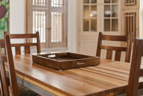 A wooden dining table with a central tray and chairs, set in a warmly lit dining area.