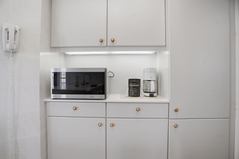 A sleek kitchenette displaying a microwave, coffee maker, and stylish cabinets.