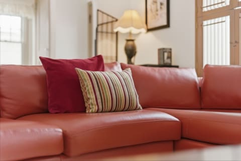 Close-up of a leather sectional sofa with vibrant pillows in a cozy living room setting.