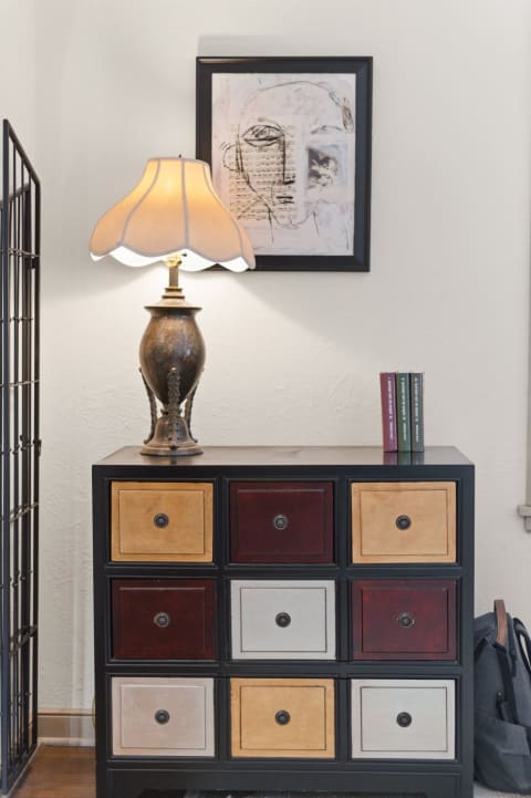 A cozy corner featuring colorful storage drawers, a brass lamp, and an abstract artwork on the wall.