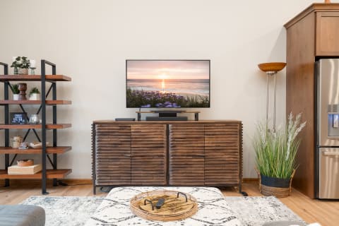 A modern living room with wooden furniture, a television displaying a sunset, and decorative plants.