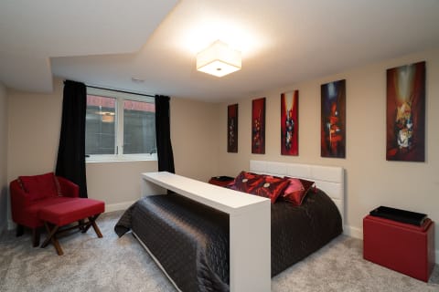 A stylish bedroom with a bed, abstract wall art, and a cozy armchair.