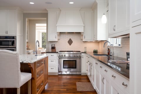 A stylish kitchen featuring white cabinetry, a granite countertop, and a stainless steel oven.