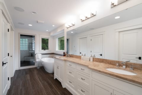 Bright and airy modern bathroom featuring a freestanding tub and a double vanity with beige countertop.