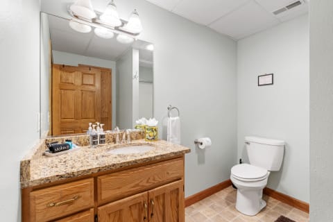 A clean and modern bathroom with a granite countertop, white toilet, and light green walls.