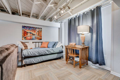 Cozy bedroom with daybed, wooden desk, and colorful wall art.