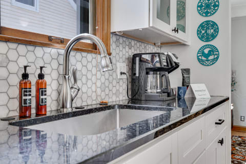 Modern kitchen countertop with stainless steel sink, coffee maker, and decorative turquoise plates.