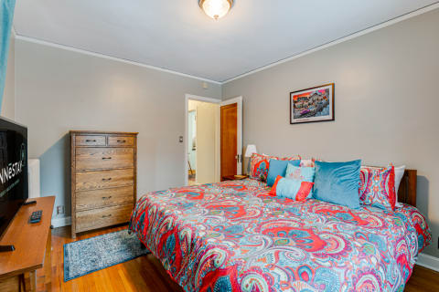 A warm and inviting bedroom with a colorful patterned bedspread and wooden furniture.