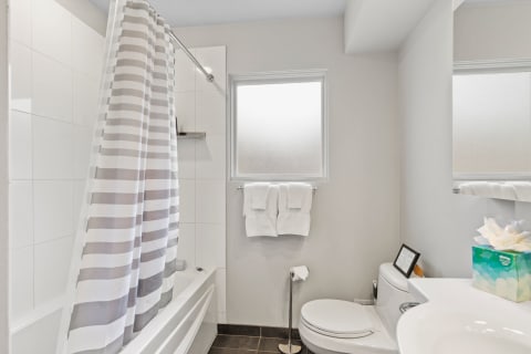Interior of a modern bathroom with a shower curtain, white towels, and minimalist decor.