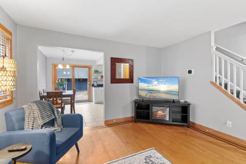 Cozy living room with a blue chair, TV, and dining area in view.
