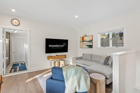Modern living room featuring a sectional sofa, accent chair, and wall-mounted TV.
