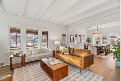 Elegant living room featuring leather seating, wooden accents, and large windows.