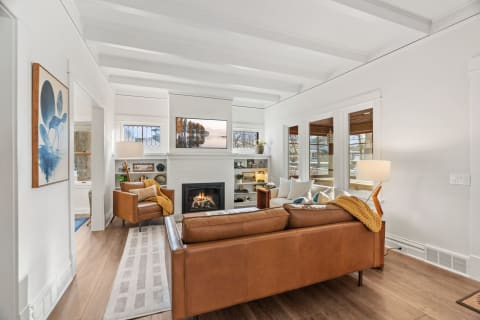 A stylish living room with a fireplace and leather furniture, showcasing modern decor and natural light.