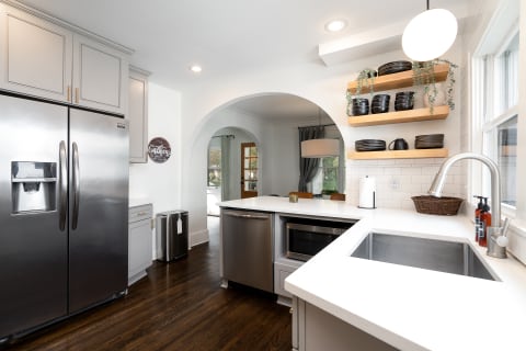 Modern kitchen with stainless steel appliances, grey cabinets, and a bright dining area.