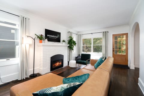 Modern living room with a leather sectional, green armchair, and fireplace.