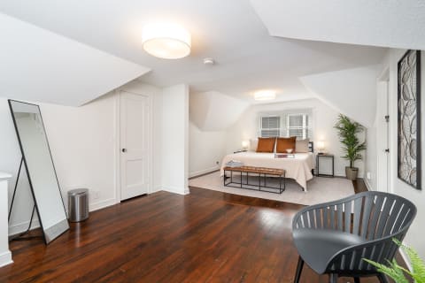 Stylish attic bedroom featuring a queen-sized bed, wooden bench, and decorative plants.