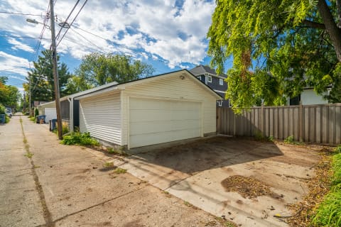 View of a white garage in an alleyway with power lines and trees.
