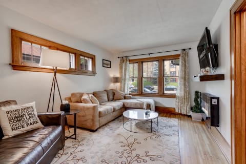 A warm and inviting living room featuring a leather couch, beige sectional, and a round coffee table on a patterned rug.