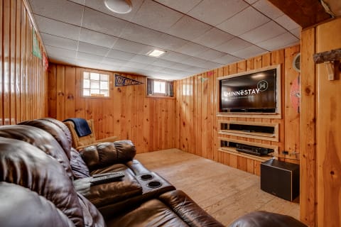Cozy basement entertainment room featuring a leather couch and a wall-mounted television.
