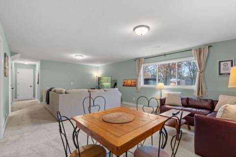 Cozy living area featuring a sectional sofa, leather couch, wooden dining table, and large windows.
