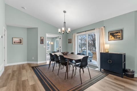Modern dining room with a light green wall, dark wood table, and black chairs.