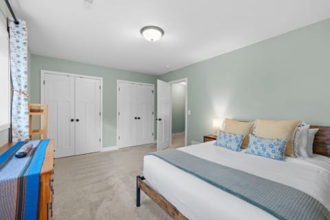 A light and airy bedroom with green walls and decorative pillows on the bed.