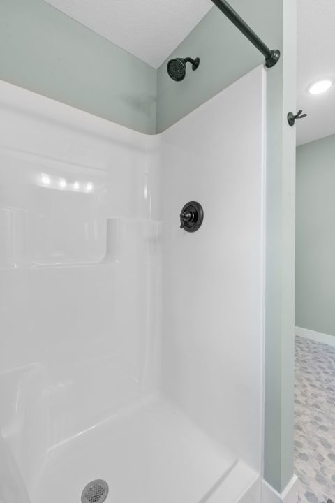 A clean and modern shower with a white enclosure and black fixtures.