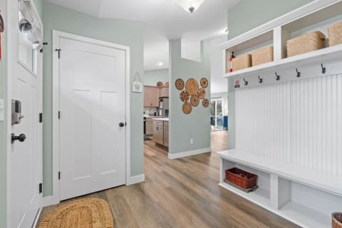 A modern entryway featuring a mudroom bench, storage baskets, and decorative wooden wall art.