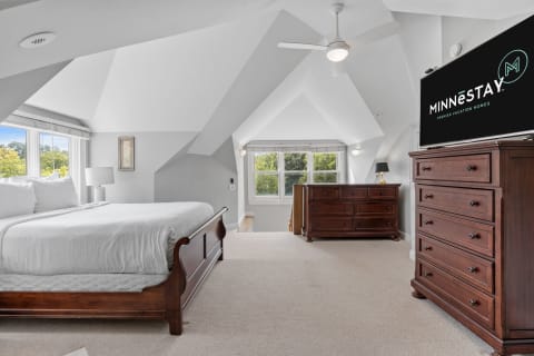 Bright and modern bedroom featuring a king-size bed, wooden furniture, and a TV with the Minnestay logo.