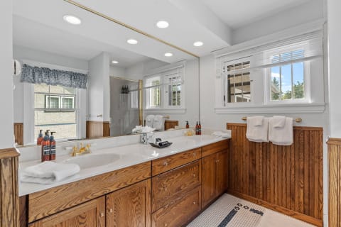 Luxurious bathroom featuring a marble countertop, wooden cabinets, a large mirror, and a glass shower.
