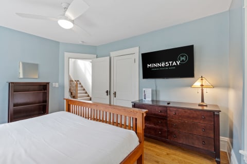 Cozy bedroom with wooden furniture, flat-screen TV, and light blue walls.