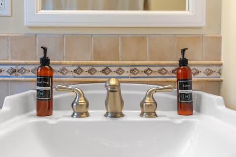 Bathroom sink with hand soap and lotion bottles beside the faucet.