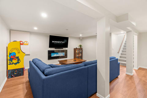 Finished basement with a sectional couch, modern fireplace, arcade game, and TV.