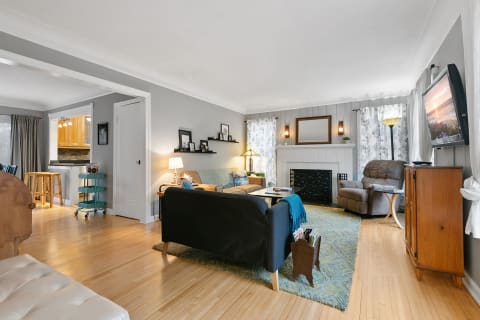 A warm-toned living room featuring a dark sofa, a recliner, and a fireplace with decorative items.