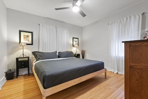 Cozy bedroom with gray bedspread, wood furniture, and natural light.